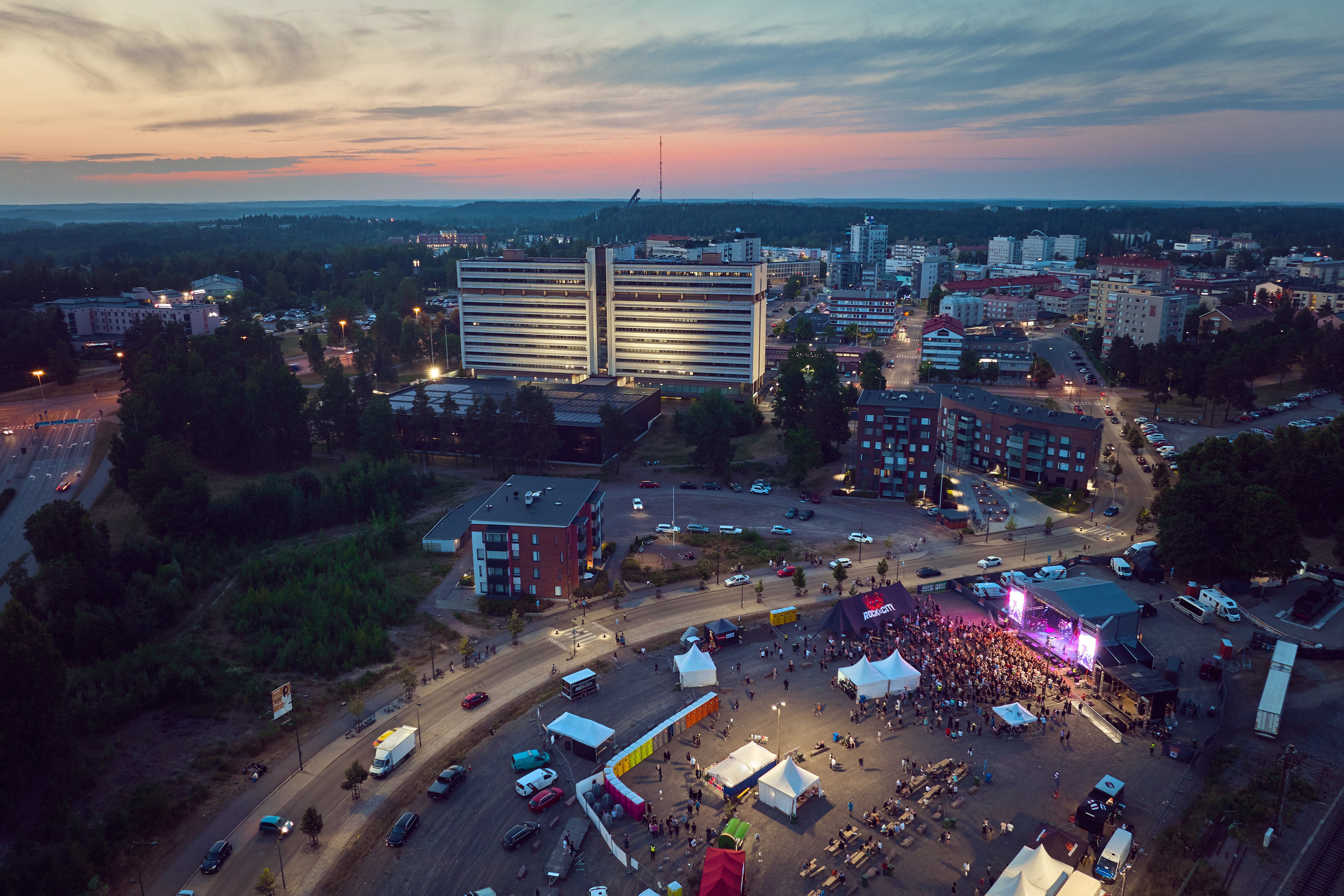 Aerial view of Kouvola, Finland at sunset, showing the city hall and a music festival.