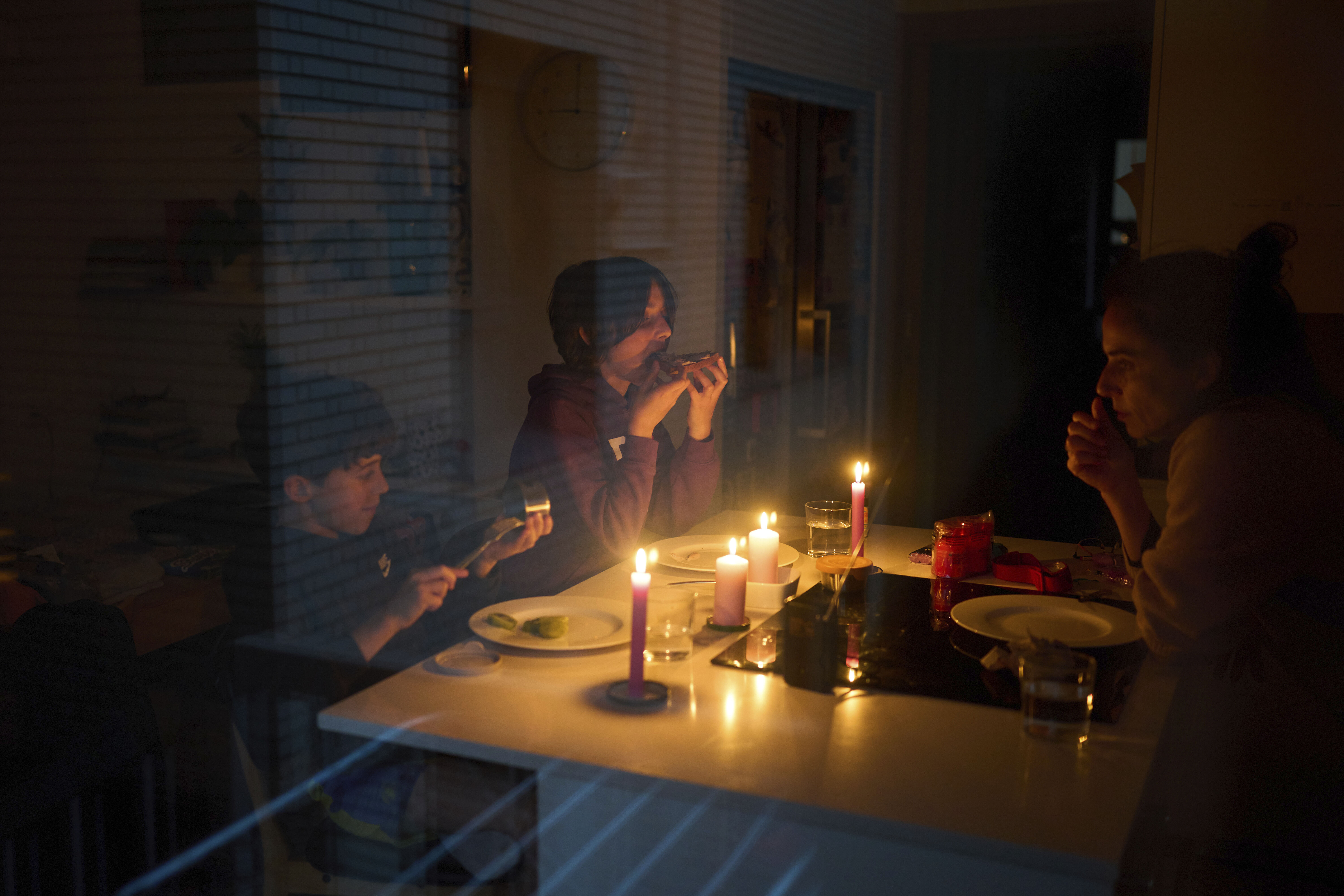 Family eating by candlelight during a blackout.