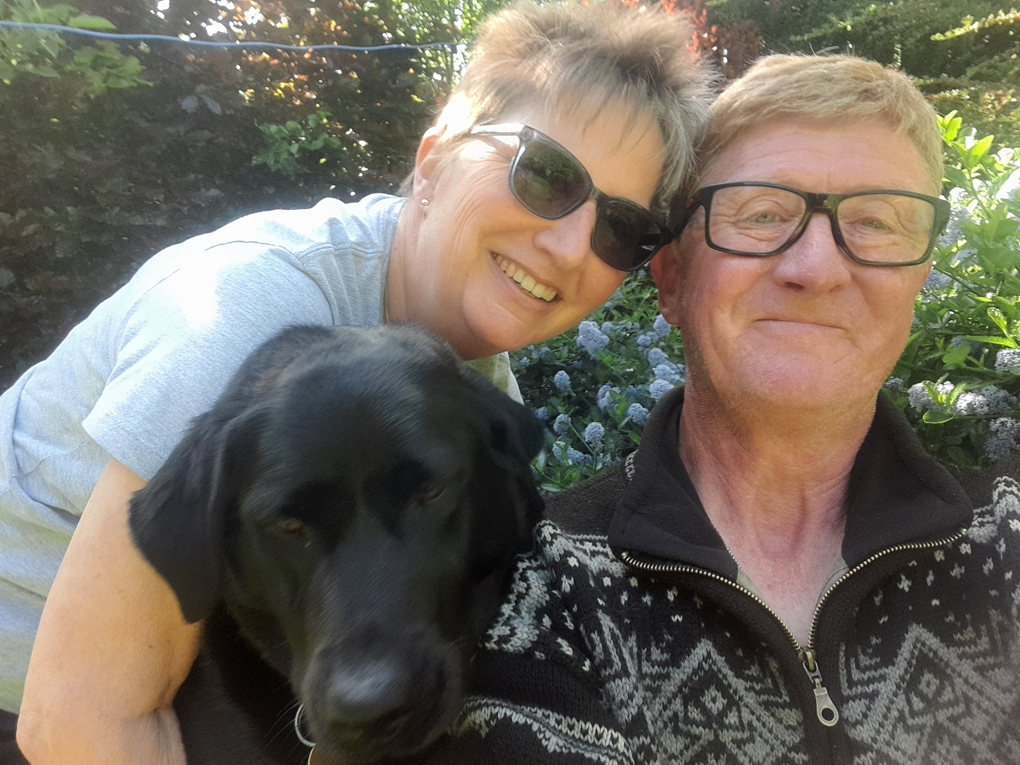 Selfie of a couple and their black Labrador.